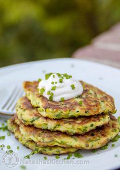 a stack of food on a white plate with a fork and some sour cream in the middle