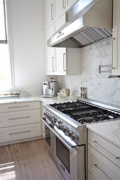 a stove top oven sitting inside of a kitchen next to white cabinets and counter tops