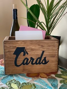 a wooden box with cards and a bottle of wine in it sitting on a bed