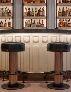 two stools in front of a bar with liquor bottles on the wall behind them