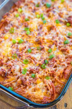 a casserole dish with meat, cheese and green onions in it on a wooden table