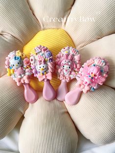 three hello kitty brooches sitting on top of a flower shaped pillow in the shape of a sunflower