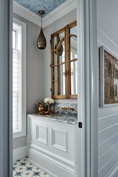 a white bathroom with blue and gold accents on the ceiling, along with marble countertops