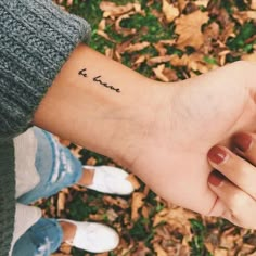 two people holding hands with the word love tattooed on them