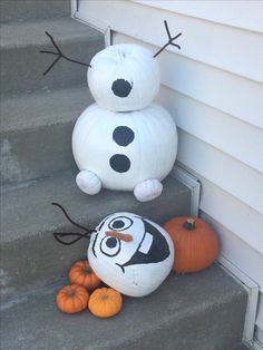 two pumpkins are sitting on the steps next to a snowman and penguin balloon