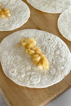 four tortillas on a wooden cutting board with pineapple slices in between them