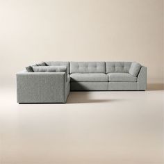 a gray sectional couch sitting on top of a white floor next to a beige wall