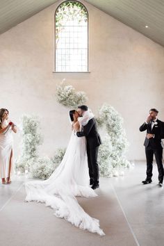 a bride and groom kissing in front of their wedding party