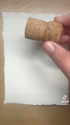 a person holding a cork in front of a piece of paper