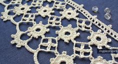 crocheted doily is laying on a blue tablecloth with beads around it