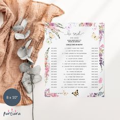 a wedding seating chart with flowers and butterflies on it next to a shawl draped over the table