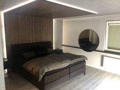 a bedroom with a bed, mirror and window in the corner on the wall next to it