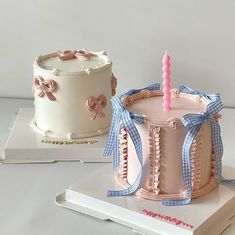 two cakes with bows on them and one has a candle in the middle, sitting on top of a book