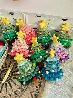 crocheted christmas trees are sitting on the floor next to some scissors and other items