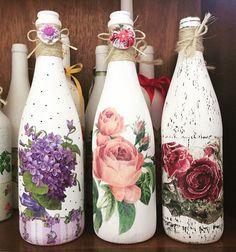 four painted wine bottles with flowers on them sitting on a shelf next to each other