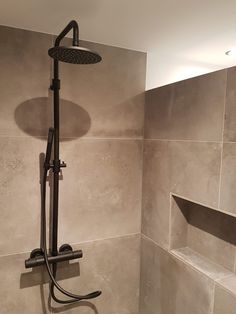 a shower head and hand held shower faucet in a tiled bathroom with gray walls