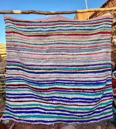 a multicolored blanket hanging from a wooden fence