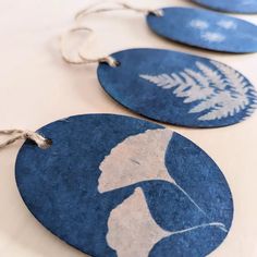 three blue ornaments with white designs are hanging from strings on a tablecloth covered table