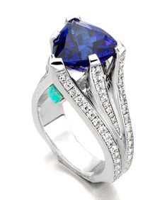 18kt white gold ring featuring a 7.97ct trillion cut tanzanite, accented with a pyramid shape opal, and 1.60ctw of white diamonds.This piece is currently in stock. Stone Ring Design, Moonstone Engagement Ring, White Gold Ring, Opal Ring, Stunning Jewellery