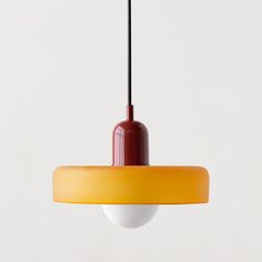 a red and yellow light hanging from a ceiling fixture with a white wall in the background