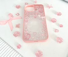 a pink phone case sitting on top of a table next to flowers and a bow