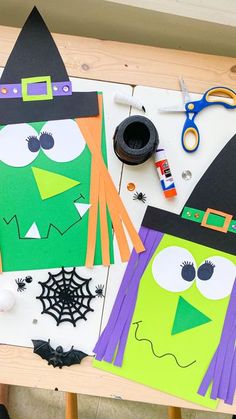 two paper bags decorated like witches on a table with scissors, glue and other crafting supplies