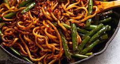 a skillet filled with noodles and green beans