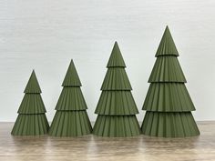 five green plastic christmas trees sitting on top of a wooden table next to each other