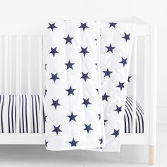 a white crib with blue stars on it and a striped pillow next to the crib