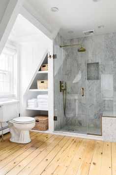 a bathroom with white walls and wood flooring next to a walk - in shower