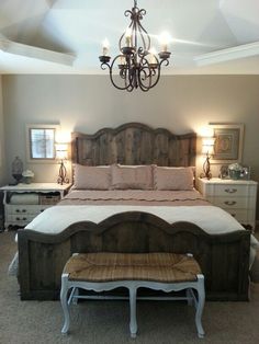 a bedroom with a bed, dressers and a chandelier hanging from the ceiling