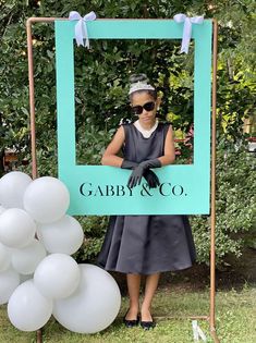 a woman standing in front of a sign that says gaby & co with balloons