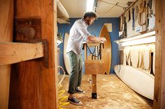 a man working on a surfboard in a shop