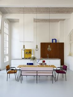 a dining table with four chairs and a bench in the middle of an empty room