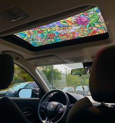 the interior of a car with a colorful stained glass skylight in the front window