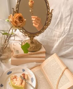 a person is holding a rose in front of a mirror and some books on a bed