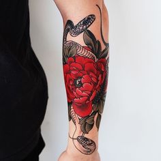 a woman's arm with a red flower and snake tattoo on her left arm