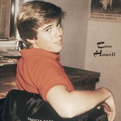 a young man sitting on top of a wooden table