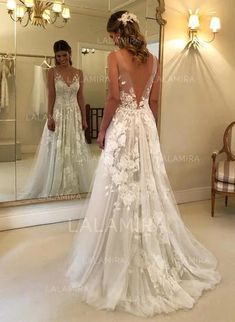 a woman standing in front of a mirror wearing a wedding dress with flowers on it