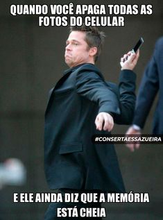 a man in a black suit is holding a cell phone and pointing to the side