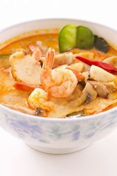 a bowl of soup with shrimp, peppers and mushrooms in it on a white background