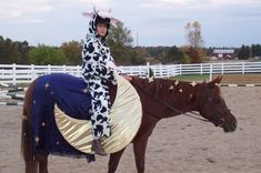 a woman dressed as a cowgirl sitting on top of a brown and white horse