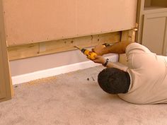 a man laying on the floor using a drill