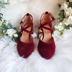 a pair of red high heeled shoes sitting on top of a white fur rug