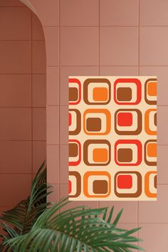 an orange and brown square pattern on a wall next to a plant