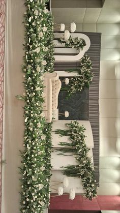 an arrangement of white flowers and greenery on the wall