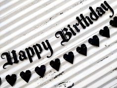 a happy birthday sign with hearts hanging from it's side on a white wall