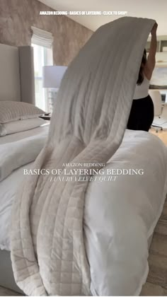 a woman laying on top of a bed covered in white sheets and blankets with the words basics of luxury bedding