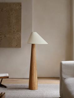 a living room with a white couch and a wooden floor lamp in the middle of it