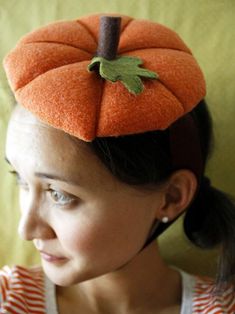 a young woman wearing an orange hat with a green leaf on it's top